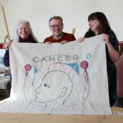 Artist Andrew Crummy and stitchers Heather Swinson and Gillian Hart show a panel from the cancer tapestry