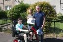Alex Brown, owner of Ideal Flooring Solutions in Musselburgh, presents a mobility scooter and Xbox to Reece Dodds. Looking on is Reece's mum Pauline