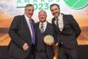 Chris Logan (centre) was presented the award by farmer Meurig Raymond, MBE (left), and comedian Patrick Monahan (right). Image: Lewis Business Media and Farm Contractor