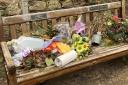 Discarded wreaths, flowers and other items on the memorial bench