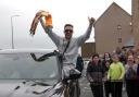 Josh Taylor holds aloft one of his world title belts in celebration as he arrives home in Prestonpans to a hero's welcome