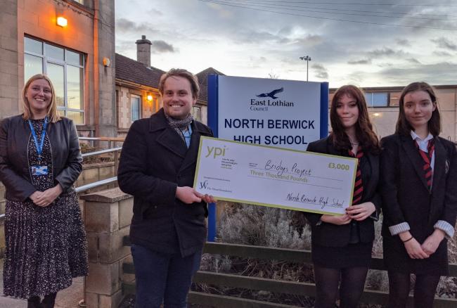 Elena Callander and Ruby Clark hand over a cheque to Simen Holm, of the Bridges Project, alongside North Berwick High School headteacher Michelle Moore