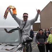 Josh Taylor holds aloft one of his world title belts in celebration as he arrives home in Prestonpans to a hero's welcome