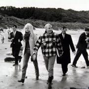 Bardot walks up a path from the beach trailed by newspaper photographers